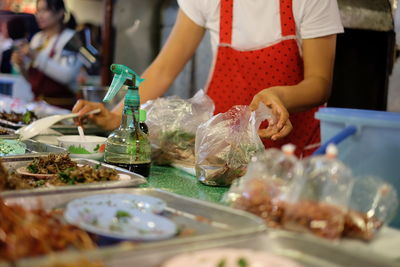 Midsection of woman packing food at market stall
