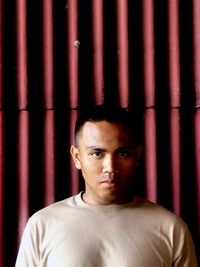 Portrait of young man standing against wall