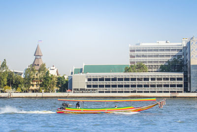 View of buildings by river against clear sky