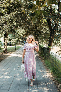 Portrait of smiling young woman walking on footpath