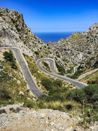 Scenic view of road by mountains against blue sky