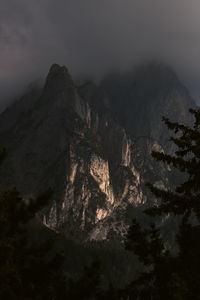 Low angle view of rocky mountains against dark sky at sunset