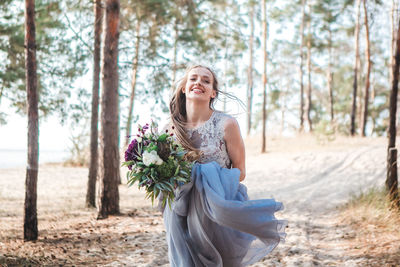 Young woman smiling while sitting on tree in forest