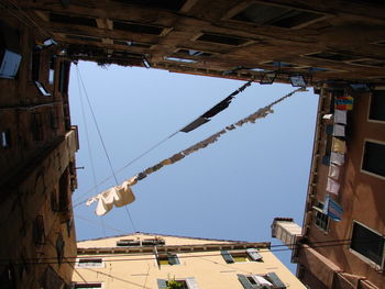 Low angle view of clothesline amidst buildings against sky