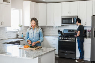 Happy friends standing by kitchen at home