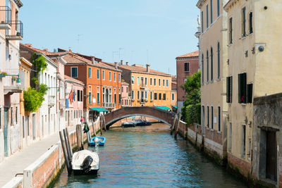 Boats moored in canal amidst buildings