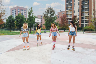 Happy friends roller skating at sports court