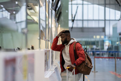 Frustrated sad young african man passenger having problems with check-in for flight