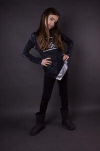 Portrait of young woman standing against black background