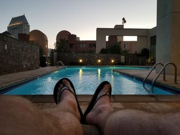 Low section of man in swimming pool against clear sky