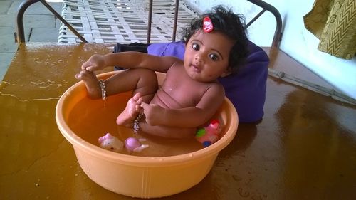 High angle portrait of baby girl in tub on cot