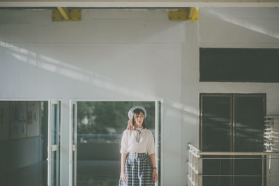 Young woman standing against wall