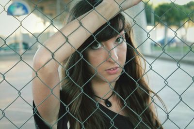Portrait of woman holding chainlink fence