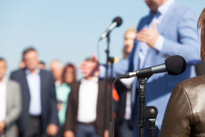 Rear view of woman standing against politician making speech to crowd