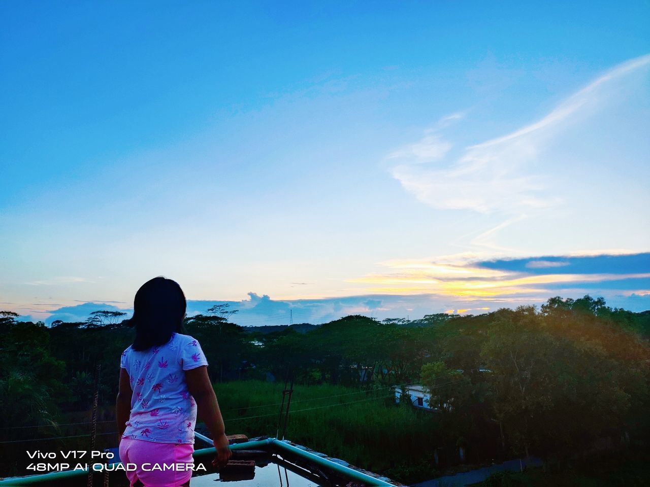 sky, one person, horizon, nature, rear view, mountain, adult, beauty in nature, morning, cloud, women, scenics - nature, blue, vacation, landscape, sunlight, leisure activity, tranquility, lifestyles, environment, standing, looking at view, water, trip, sea, dusk, tranquil scene, holiday, architecture, land, outdoors, clothing, person, travel, copy space, relaxation, tree, child, casual clothing, female, travel destinations, three quarter length, mountain range, waist up, reflection, childhood, activity, day