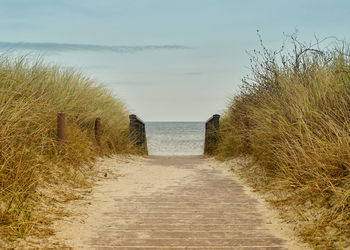 Footpath amidst sea against sky