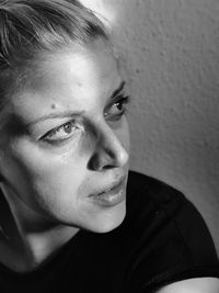 Close-up of woman looking away against wall