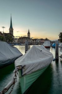 Boats moored in river with church in background