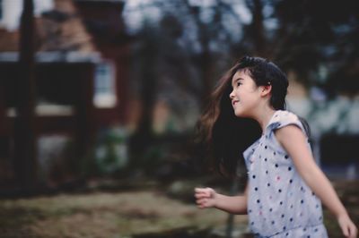 Cute smiling girl looking away while standing outdoors