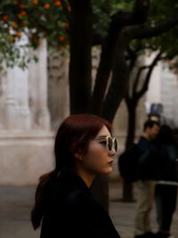 Portrait of woman standing against tree