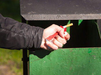 Close-up of man throwing cigarette in garbage bin