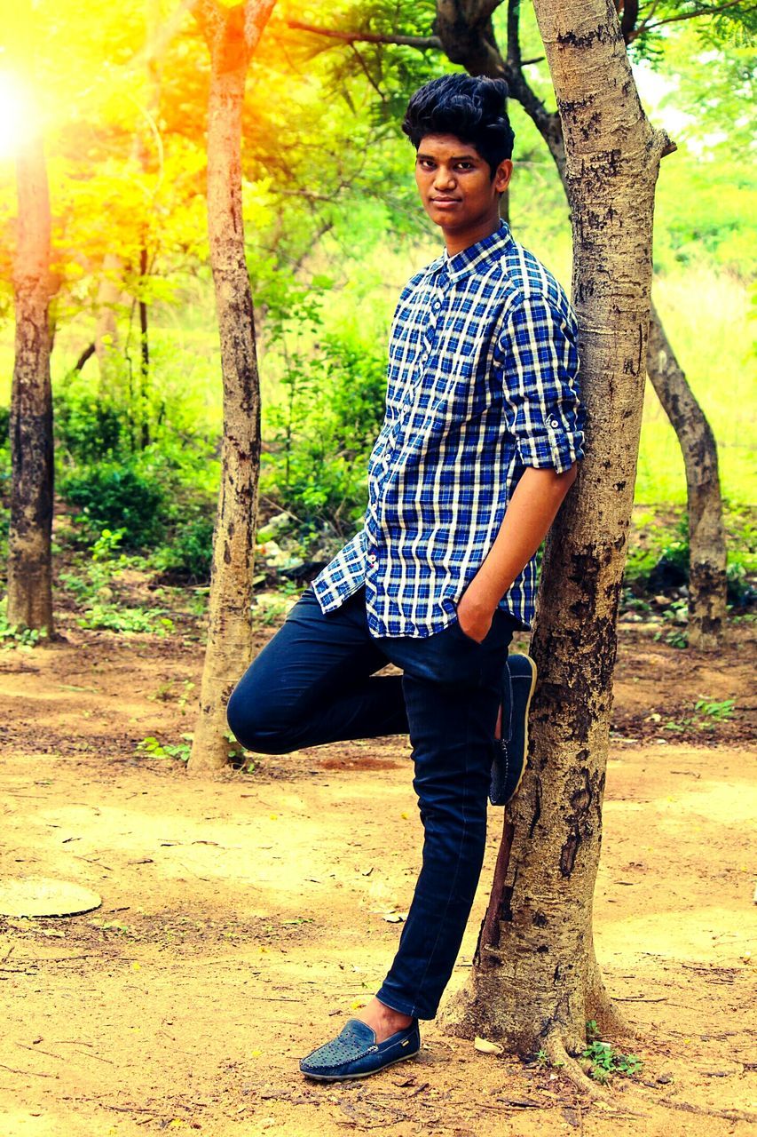 PORTRAIT OF HAPPY YOUNG MAN STANDING IN FOREST