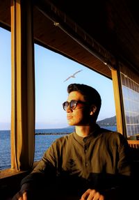 Portrait of young man looking away against window