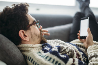 Man lying on a couch looking at smartphone