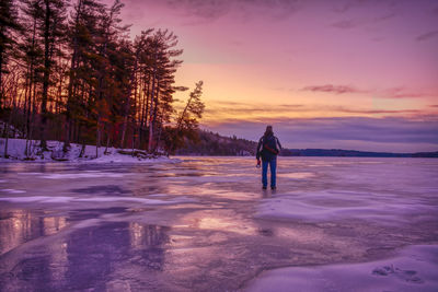 Rear view of person standing in snow during sunset