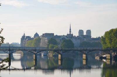 Bridge over river in city against sky