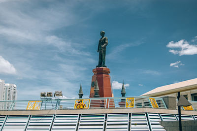 Low angle view of statue by building against sky