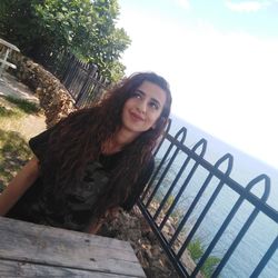 Portrait of smiling young woman against railing