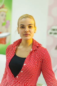 Portrait of young woman standing against wall