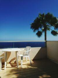 Chairs and tables on beach against clear blue sky