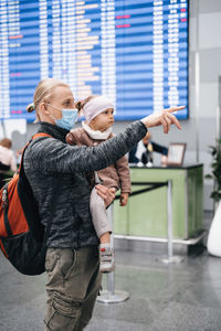 Man and girl watching timetable information at the airport, passengers waiting for a plane. family