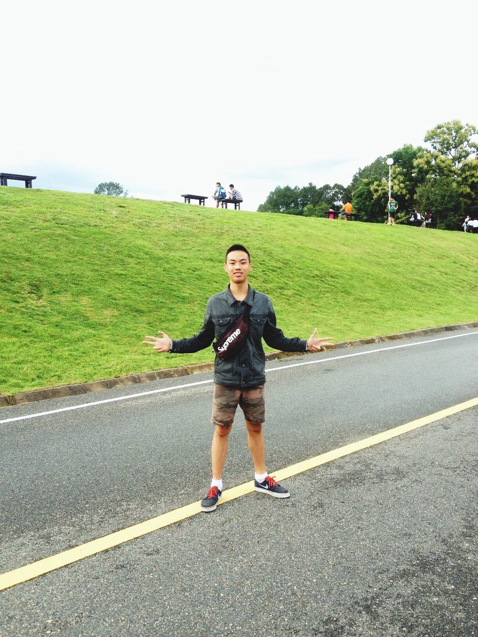 full length, person, casual clothing, lifestyles, looking at camera, portrait, leisure activity, front view, road, smiling, childhood, happiness, street, elementary age, young adult, grass, standing, clear sky