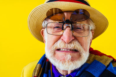 Senior man clenching teeth against yellow background