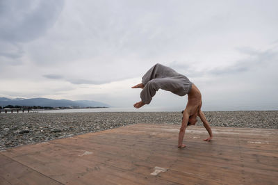 Side view of woman standing at beach against sky