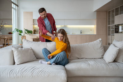 Young woman using phone while sitting on sofa at home