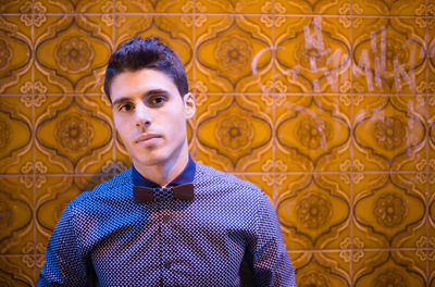 Portrait of young man standing against tiled wall