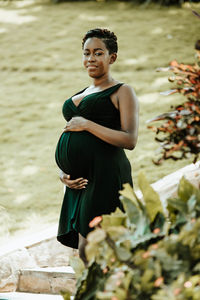 Portrait of young pregnant woman standing by plants