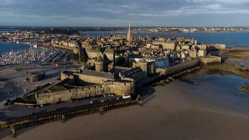 High angle view of city by sea against sky