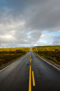 Road along landscape against cloudy sky