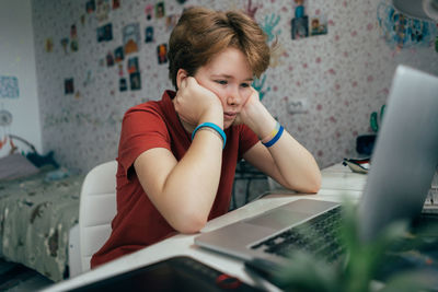 Teenage girl uses video chat on laptop while sitting at home.