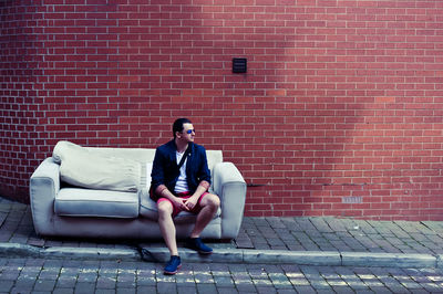 Full length of a woman sitting on brick wall