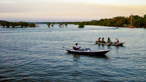 People on boat in lake against sky