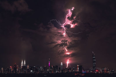 Firework display in city against sky at night