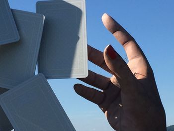 Low angle view of hand holding umbrella against sky