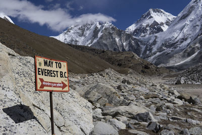 Information sign on snowcapped mountains against sky