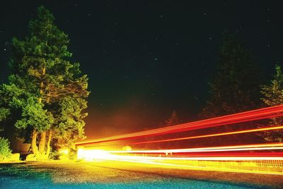 Light trails on road against sky at night